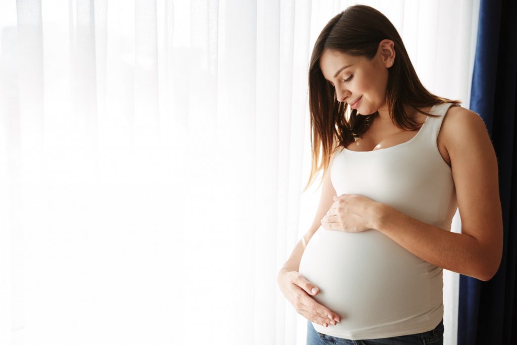 Mulher grávida com a mão na barriga 